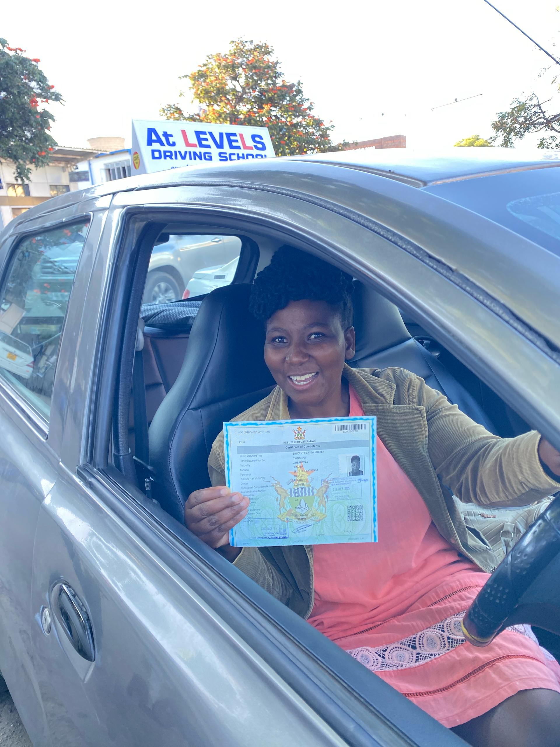 Happy woman holding a driver's license next to a car